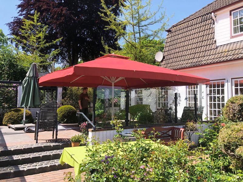 Gartenterrasse am Haus mit einem großen Sonnenschirm und angrenzendem Grün