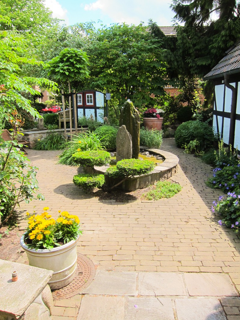 Gartenweg mit Formgehölzen und Wasserspiel im Bürogarten von Eskildsen Gärten in Malente